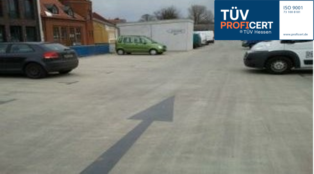 Außenparkplatz mit Richtungspfeil und TÜV PROFiCERT-Siegel oben rechts.