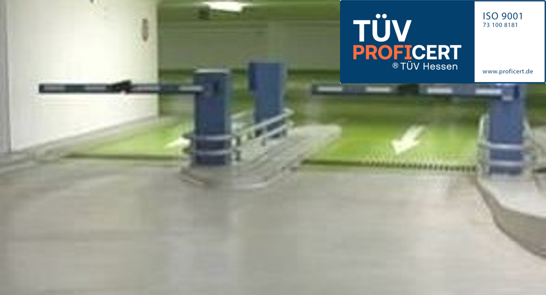 Einfahrt einer Tiefgarage mit Schranken und TÜV PROFiCERT-Siegel.