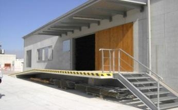 Verladerampe mit Treppe an einem Industriegebäude bei Sonnenschein.