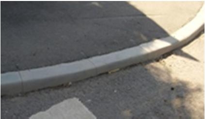 Nahaufnahme einer Bordsteinkante an asphaltierter Straße.