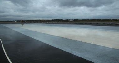 Weite Testfläche mit rutschigem Belag unter bewölktem Himmel.